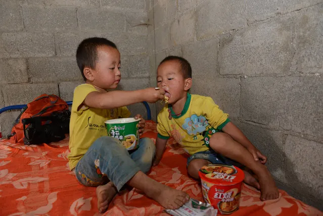 A child feeds his companion with instant noodles after they were evacuated from the site of a landslide in Bijie, Guizhou province, China, July 1, 2016. (Photo by Reuters/Stringer)
