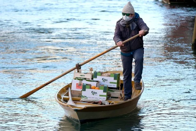 A man delivers fruits and vegetables by rowboat to his customers' houses during the current emergency of the coronavirus disease (COVID-19) in Venice, Italy, March 25, 2020. (Photo by Manuel Silvestri/Reuters)