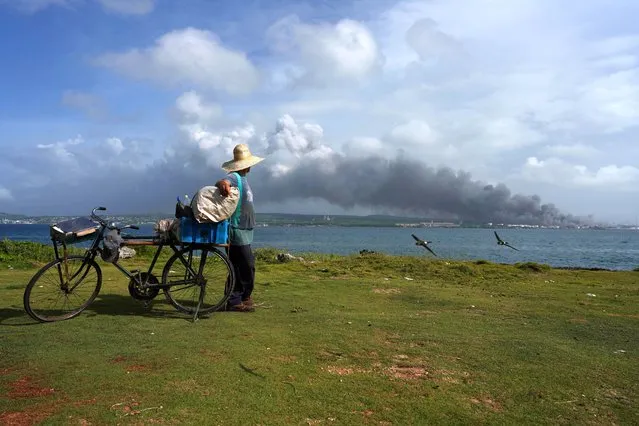 A man observes the smoke from the zone where fuel storage tanks exploded near Cuba's supertanker port in Matanzas, Cuba on August 9, 2022. (Photo by Alexandre Meneghini/Reuters)