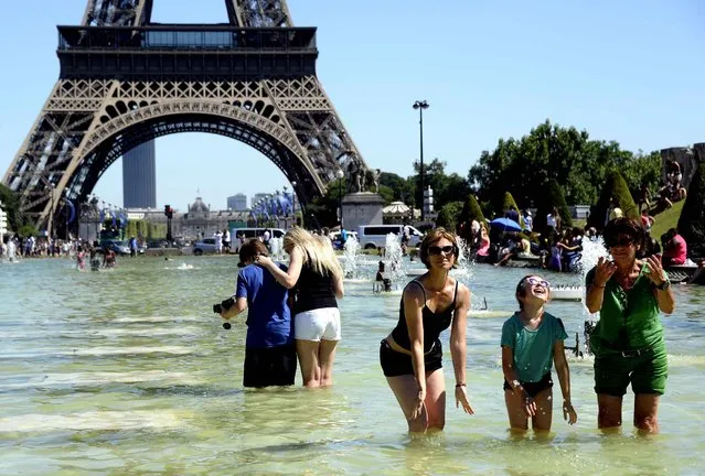 People refresh in the water of the Trocadero fountains in front of the Eiffel tower in Paris as summer temperature raises on July 19, 2016. (Photo by Bertrand Guay/AFP Photo)