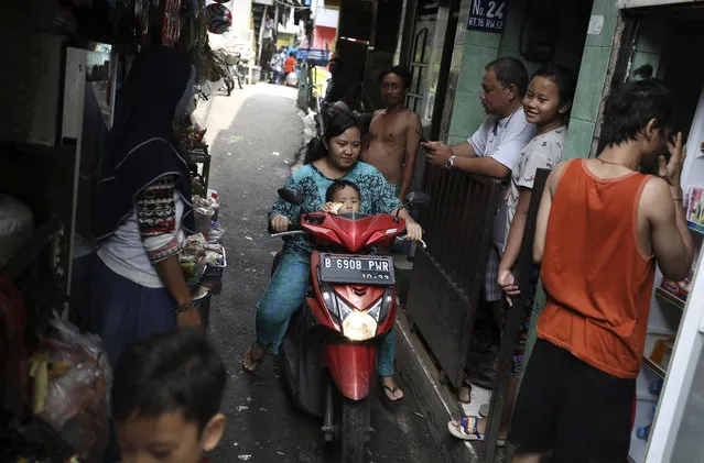 A motorist rides past as residents talk on an alley at a low-income neighborhood in Jakarta, Indonesia, March 23, 2020. As the virus spreads, the World Health Organization has pointed out that the future of the pandemic will be determined by what happens in some of the world’s poorest and most densely populated countries. From Mumbai to Rio de Janeiro to Johannesburg the question is: What do you do if there is no space to socially distance yourself from others in some of world’s most unequal regions? (Photo by Dita Alangkara/AP Photo)