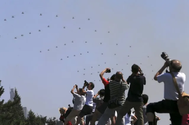 People take pictures as military helicopters fly across the sky during the military parade marking the 70th anniversary of the end of World War Two, in Beijing, China, September 3, 2015. (Photo by Reuters/Stringer)