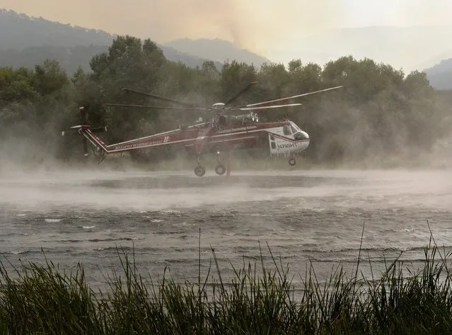 A helicopter fills up with water from a pond at Rancho San Carlos before heading off to fight a wildfire in Carmel Valley, Calif., Wednesday, July 27, 2016. Acting Gov. Tom Torlakson, substituting for Gov. Jerry Brown who is at the Democratic National Convention with other top state officials, declared a state of emergency for the fire and another wildfire outside of Los Angeles on Tuesday night. The move frees up funding and relaxes regulations to help with the firefight and recovery. (Photo by David Royal/The Monterey County Herald via AP Photo)