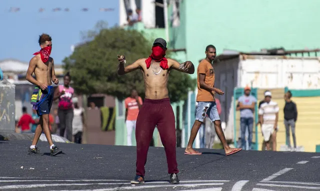 Residents of Mitchell's Plain in Cape Town, South Africa, Clash with police Tuesday, April 14, 2020, in protest against the distribution of food parcels to the poor and unemployed during the third week of a lockdown to control the spread of coronavirus. (Photo by AP Photo/Stringer)