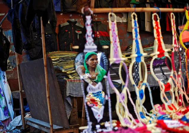 A woman is reflected in a mirror as she buys decorations for her home at a market in the old quarters of Delhi, India July 28, 2016. (Photo by Adnan Abidi/Reuters)