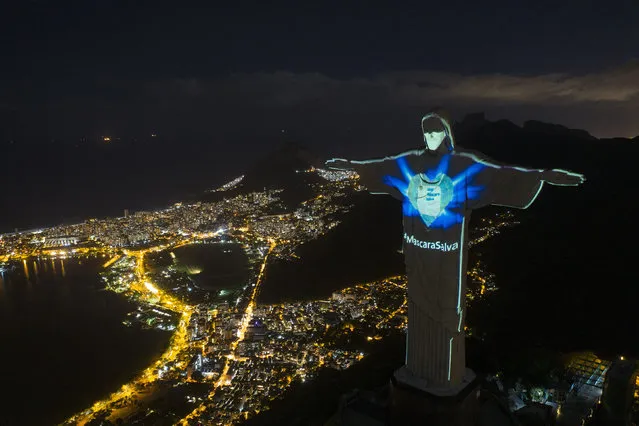 Rio's Christ the Redeemer statue is lit up as if wearing a protective mask amid the new coronavirus pandemic, in Rio de Janeiro, Brazil, Sunday, May 3, 2020. The message “Mask saves” is written in Portuguese. (Photo by Leo Correa/AP Photo)