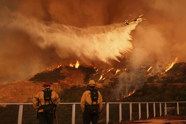 Firefighters watch a helicopter drop water on the Palisades Fire in Mandeville Canyon in Los Angeles, on Saturday, January 11, 2025. (Photo by Jae C. Hong/AP Photo)
