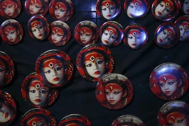 Badges with portraits of the living goddess Kumari are seen on sale along a street during the Indra Jatra festival in Kathmandu September 8, 2014. The annual festival, named after Indra, the god of rain and heaven, is celebrated by worshipping, rejoicing, singing, dancing and feasting in Kathmandu Valley to mark the end of monsoon season. Indra, the living goddess Kumari and other deities are worshipped during the festival. (Photo by Navesh Chitrakar/Reuters)