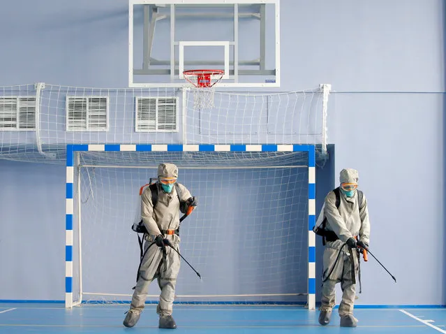 Belarus Ministry of Defence service members disinfect a school gym, in protective gear, as the spread of coronavirus disease (COVID-19) continues, in the village of Borovlyany, Belarus on May 2, 2020. (Photo by Vasily Fedosenko/Reuters)