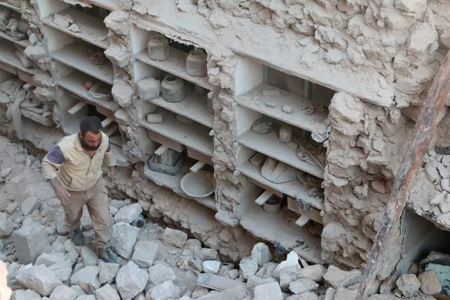 A civil defence member looks for survivors amid rubble of damaged houses after an airstrike on rebel held Old Aleppo, Syria July 16, 2016. (Photo by Abdalrhman Ismail/Reuters)