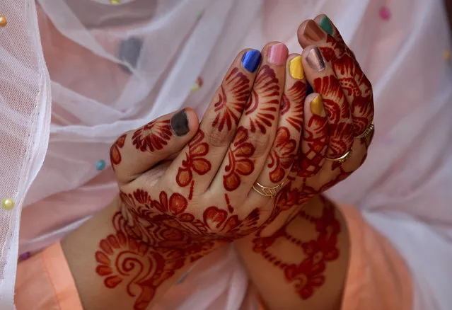 A woman, her hands decorated with traditional henna, prays during Eid al-Fitr prayer at historical Badshahi mosque in Lahore, Pakistan, Sunday, May 24, 2020. (Photo by K.M. Chaudary/AP Photo)