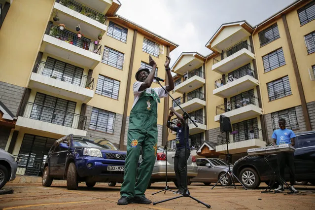 Rev. Paul Machira preaches and sings to residents in an apartment block in Nairobi, Kenya, Sunday, May 17, 2020. The Kenyan pastor has taken his church service for children on the road due to coronavirus restrictions and preaches from parking lots outside apartment buildings while kids and their parents dance on balconies above. (Photo by Brian Inganga/AP Photo)