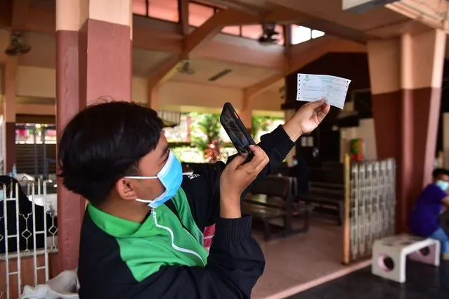 A passenger takes a photo of his ticket during the return of train services in the region, following the lifting of travel restrictions to halt the spread of the COVID-19 coronavirus, at Tanyong Mat railway station in the southern Thai province of Narathiwat on June 11, 2020. (Photo by Madaree Tohlala/AFP Photo)