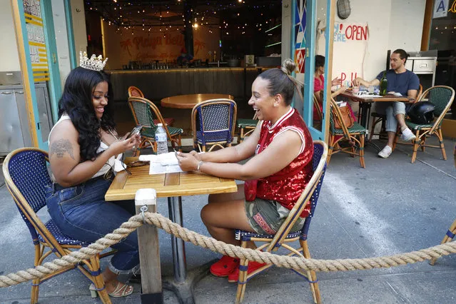 Maya Evans, right, celebrates with friend Tifffany Webster, 30, on Webster's 30th birthday during the first day of the city's phase two reopening from the coronavirus outbreak, Monday, June 22, 2020, on the Upper West Side of Manhattan in New York. Under phase two, the city's restaurants are allowed to serve patrons for outdoor dining with some precautions and restrictions. (Photo by Kathy Willens/AP Photo)