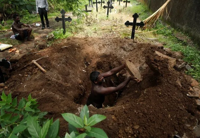A gravedigger empties out mud as he digs a grave for the burial of a person who died from coronavirus at a cemetery in Mumbai, India on June 27, 2020. (Photo by Francis Mascarenhas/Reuters)