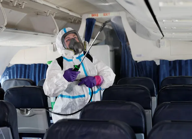 A worker wearing protective gear sprays disinfectant inside a plane at the Boryspil International Airport outside Kiev, Ukraine June 13, 2020. The airport prepares to resume regular international and domestic flights as Ukraine eases restrictions aimed to contain the spread of the coronavirus disease (COVID-19). (Photo by Gleb Garanich/Reuters)