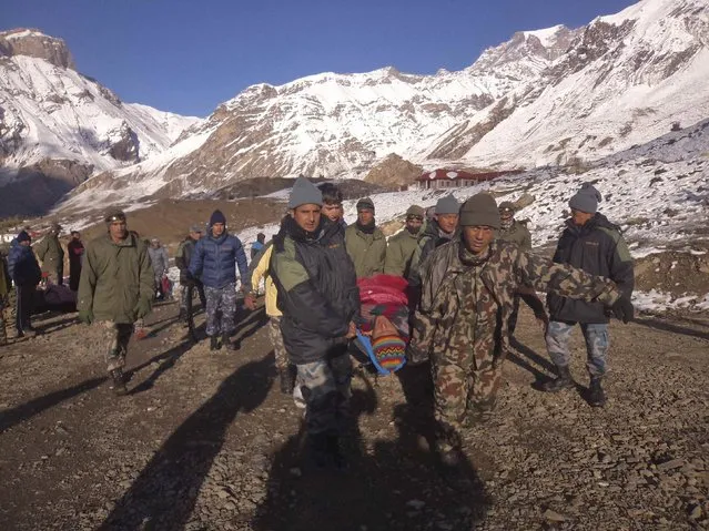 Nepalese army personnel carry a victim rescued from the avalanche at Thorang-La in Annapurna Region in this October 15, 2014 handout photo provided by Nepal Army. At least 12 people, including eight foreign hikers and a group of yak herders, were killed in Nepal by unseasonal blizzards and avalanches triggered by the tail of cyclone Hudhud, officials said on Wednesday. (Photo by Reuters/Nepalese Army)