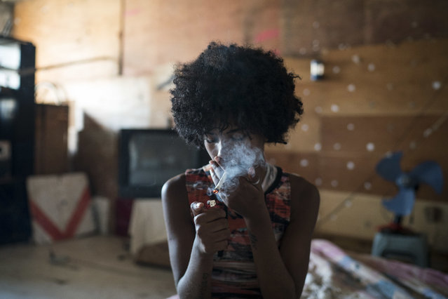 In this September 16, 2017 photo, Leticia, 15, smokes a cigarette inside a building that used to house the Brazilian Institute of Geography and Statistics (IBGE) in the Mangueira slum of Rio de Janeiro, Brazil. The squatter building is just a short walk from iconic Maracana Stadium. (Photo by Felipe Dana/AP Photo)