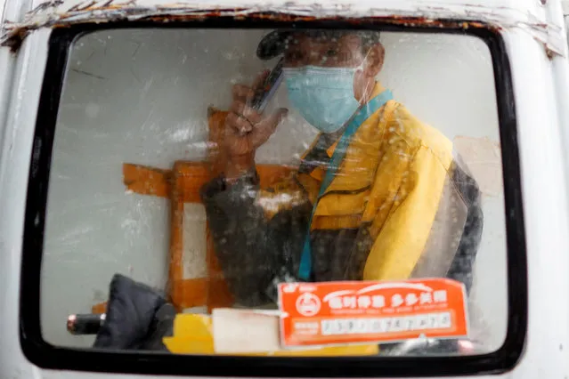 A delivery driver speaks on the phone as he sits in the cabin of his electric delivery vehicle on a rainy day following an outbreak of the coronavirus disease (COVID-19) in Beijing, China, July 9, 2020. (Photo by Thomas Peter/Reuters)