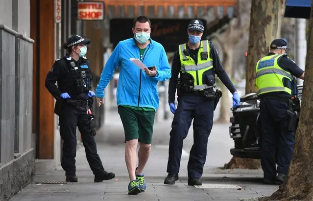 Police issue a fine to a man breaking lockdown laws in Melbourne on August 9, 2020, as the city struggles to cope with a COVID-19 coronavirus outbreak. Australia's worst-hit Victoria state reported 17 deaths from coronavirus on August 9, making it the country's deadliest day of the pandemic despite a fall in new case numbers. (Photo by William West/AFP Photo)
