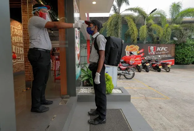 A delivery staff member wearing a protective mask is checked with a thermal scanner at the main entrance of a KFC fast food outlet, amid concerns about the spread of the coronavirus disease (COVID-19), in Colombo, Sri Lanka, July 9, 2020. (Photo by Dinuka Liyanawatte/Reuters)