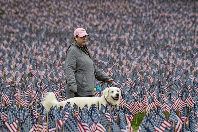 A woman walks her dog in a field of 37,000 US Flags, meant to represent every Massachusetts service member who gave their life since the Revolutionary War, at the Soldiers & Sailors Monument on Boston Common in Boston, Massachusetts on May 21, 2025. (Photo by Joseph Prezioso/AFP Photo)