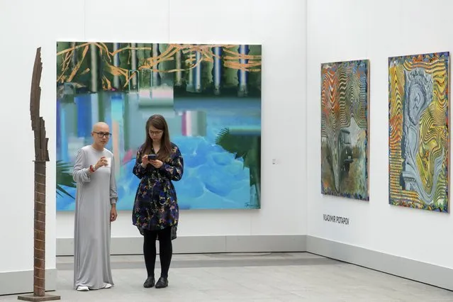 Visitors stand near artworks by Vladimir Potapov during the Cosmoscow international fair in Moscow, Russia, 10 September 2020. (Photo by Sergei Ilnitsky/EPA/EFE)