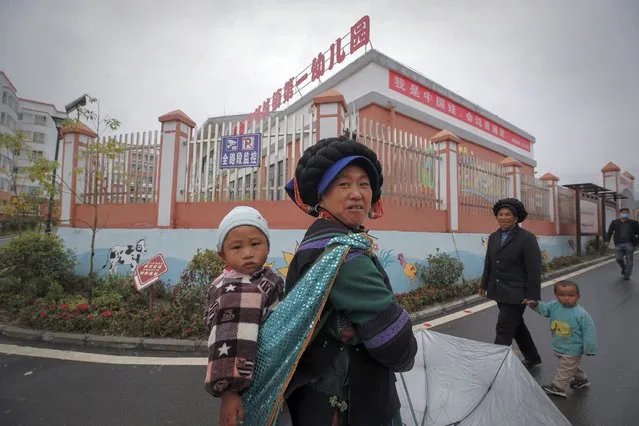 Ethnic minority women walk with their child near a kindergarten with a banner which reads “I'm a China doll, can speak Mandarin” at the apartment houses compound built by the Chinese government in Yuexi county, southwest China's Sichuan province on September 11, 2020. (Photo by Andy Wong/AP Photo)