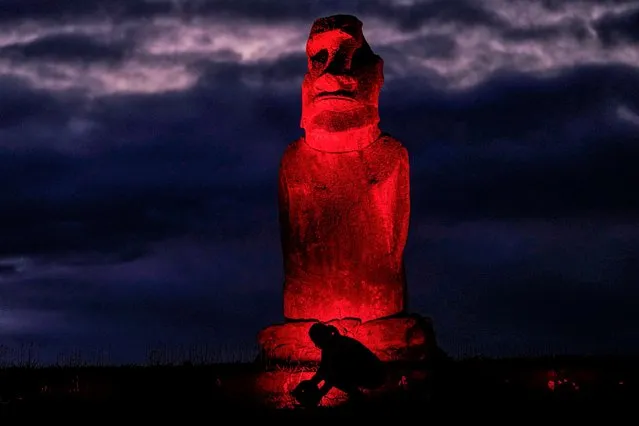 A city worker installs a light to illuminate a Moai one day before International Day for the Elimination of Violence against Women, in Hanga Roa, Rapa Nui or Easter Island, Thursday, November 24, 2022. (Photo by Esteban Felix/AP Photo)