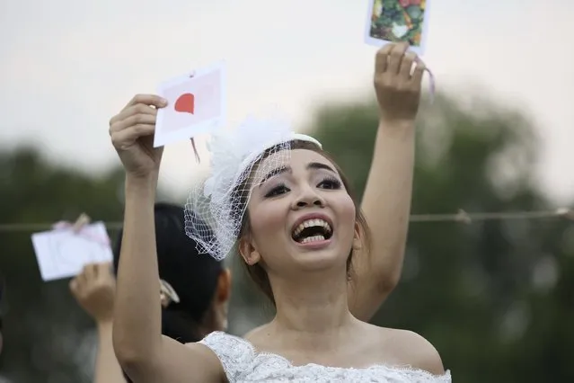 A woman gestures to her fiance during the “Running of the Brides” race in a park in Bangkok November 29, 2014. (Photo by Damir Sagolj/Reuters)