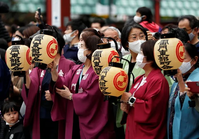 Revellers wearing protective face masks wait for the arrival of a Mikoshi or portable shrine which is carried by a truck, while usually it's carried by hands of revellers, under the infection control measures during Sanja Matsuri, one of the Tokyo's biggest traditional festivals, taking place after months of delay caused by the coronavirus disease (COVID-19) outbreak, in front of Kaminari-mon gate at Asakusa district in Tokyo, Japan on October 18, 2020. (Photo by Issei Kato/Reuters)