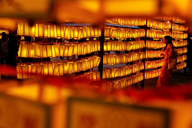 A woman in yukata, or casual summer kimono, poses to take a photo between paper lanterns during the annual Mitama Festival at the Yasukuni Shrine, where more than 2.4 million war dead are enshrined, in Tokyo, Japan on July 13, 2025. (Photo by Manami Yamada/Reuters)