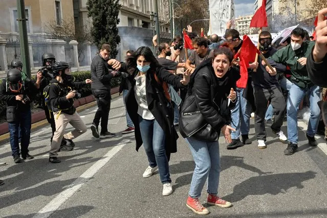 Protesters shout towards gas-throwing riot police during a massive demonstration in Athens on March 5, 2023, following the deadly train accident late on February 28. The toll from Greece's worst rail accident rose to 57 victims after a head-on collision blamed on “human error”, that has sparked angry protests. (Photo by Louisa Gouliamaki/AFP Photo)