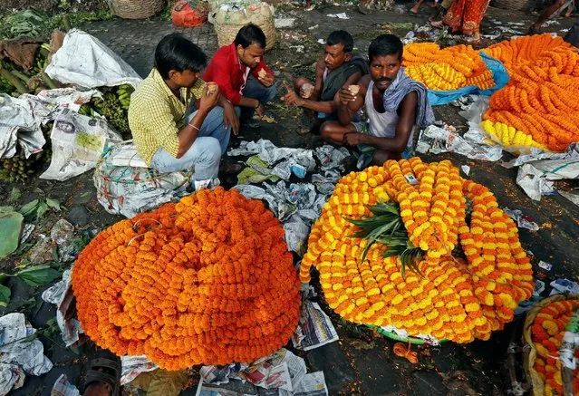 Vendors selling marigold garlands, which are used to decorate temples and homes during the Hindu festival of Durga Puja, drink tea as they wait for customers at a wholesale flower market in Kolkata, India October 6, 2016. (Photo by Rupak De Chowdhuri/Reuters)