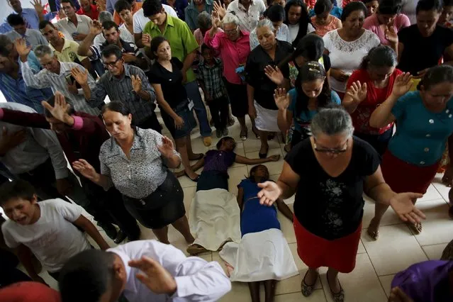 People pray during a mass in an evangelical church in the village of Rio Pardo next to Bom Futuro National Forest, in the district of Porto Velho, Rondonia State, Brazil, August 30, 2015. (Photo by Nacho Doce/Reuters)