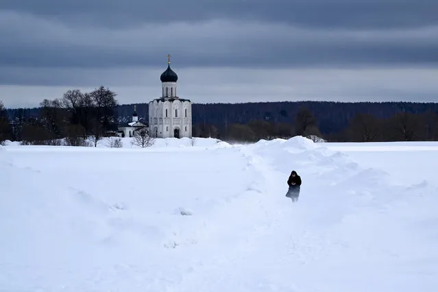 A woman walks on a snow-covered meadow in front of the 12th century Pokrova on Nerli Orthodox cathedral outside the city of Vladimir some 200 km from Moscow on March 8, 2023. (Photo by Kirill Kudryavtsev/AFP Photo)