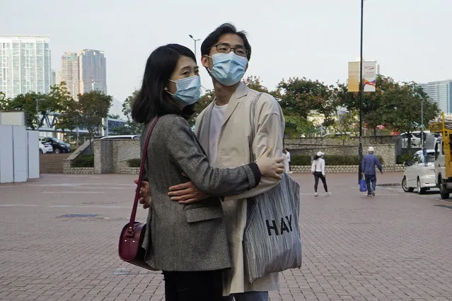 A couple wearing face masks to protect against the coronavirus embrace on a street in Hong Kong, Monday, November 30, 2020. (Photo by Kin Cheung/AP Photo)