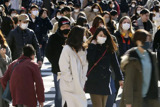 People wearing face masks to help curb the spread of the coronavirus walk around the scrambled intersection at the Shibuya shopping district in Tokyo Saturday, December 26, 2020. Tokyo has confirmed 949 new cases of the coronavirus on Saturday, a record high for the Japanese capital, as the country struggles with an upsurge that is spreading nationwide. (Photo by Kyodo News via AP Photo)
