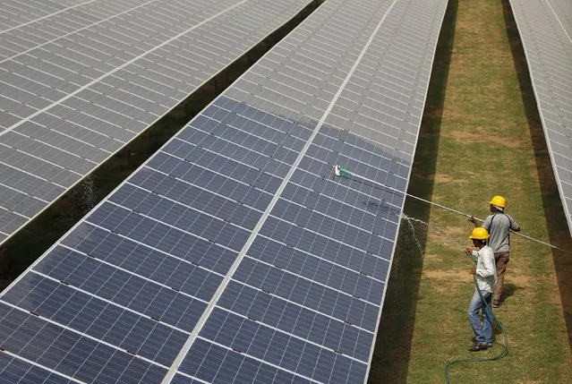 Workers clean photovoltaic panels inside a solar power plant in Gujarat, India, July 2, 2015. India's $100 billion push into solar energy over the next decade will be driven by foreign players as uncompetitive local manufacturers fall by the wayside, no longer protected by government restrictions on the sector. (Photo by Amit Dave/Reuters)
