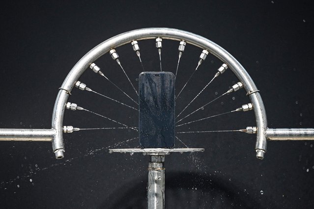 This photo taken on October 22, 2025 shows a machine conducting a waterproof test on an Honor Magic 8 smartphone at a laboratory of Chinese smartphone company Honor in Shenzhen, in southern China's Guangdong province. (Photo by Jade Gao/AFP Photo)