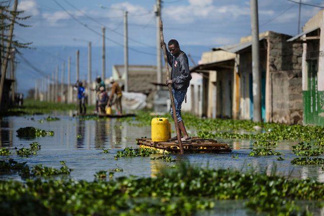 Residents use push poles to manuever their makeshift rafts over a flooded access road to their residential blocks at Kohoto estate in Naivasha on November 17, 2025. Heavy rains in Kenya have caused the waters of Lake Naivasha, a hundred kilometres northwest of capital Nairobi, to flood nearby homes, displacing families. (Photo by Tony Karumba/AFP Photo)
