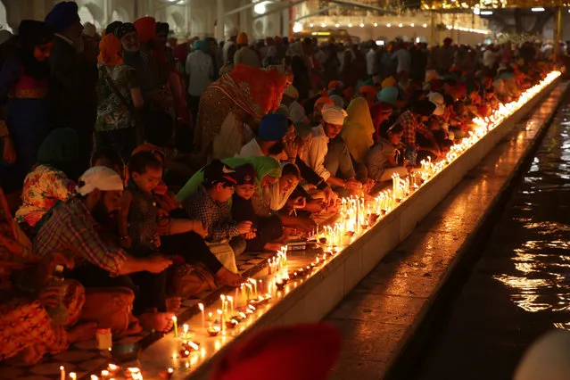 Devotees light lamps and candles near the sacred pond of the illuminated Golden Temple, the holiest of Sikh shrines, on the occasion of Diwali festival and Bandi Chorh Diwas in Amritsar, India, 30 October 2016. Devotees started to visit the Golden Temple from pre-dawn hours to seek blessings on Diwali festival. The festival coincides with the Bandi Chorh Diwas which is also celebrated at the Golden Temple to mark the return of Guru Hargobind, the sixth Guru or the Master of the Sikhs, to Amritsar after his release from Gwalior fort during the reign of Mughal emperor Jahangir. (Photo by Raminder Pal Singh/EPA)