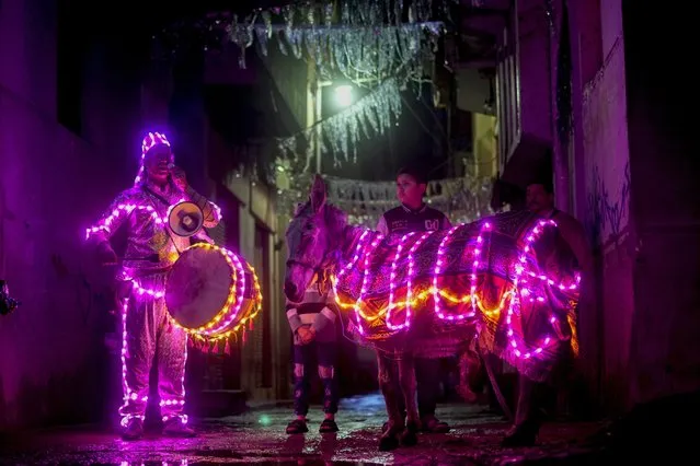 Mohammed El-Dahshan, 38-year-old “Mesaharati”, or dawn caller, accompanies his donkey wrapped with colored led lights to wake Muslims up for a meal before sunrise, during the Islamic holy month of Ramadan, in the Delta city of Dikernis, about 93 miles (150 km) North of Cairo, Egypt early Wednesday, April 12, 2023. Each night, El-Dahshan, sets out after midnight with his donkey banging his drum, chanting traditional religious phrases and calling out on residents by name to wake them in time for the vital pre-dawn meal known as “Suhour”. (Photo by Amr Nabil/AP Photo)