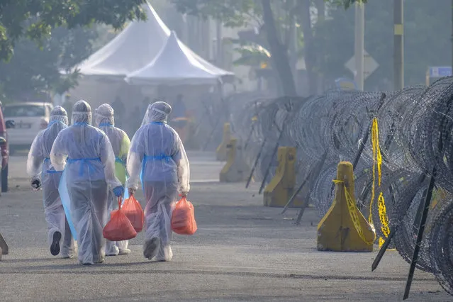 Volunteers wearing protective suits distribute food to the Top Glove workers during the lockdown in Klang, Malaysia on November 23, 2020. Food distribution by volunteers at Top Glove workers hostel after it had been locked down. Selangor has recorded its highest number of Coronavirus infection with 603 positive cases and most of the cases involve the Top Glove workers. (Photo by Faris Hadziq/SOPA Images/LightRocket via Getty Images)