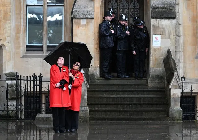 Westminster staff and police take cover from the rain as preparations continue for The Coronation on May 5, 2023 in London, England. The Coronation of King Charles III and The Queen Consort will take place on May 6, part of a three-day celebration. (Photo by Charles McQuillan/Getty Images)