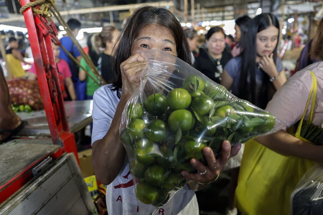 A person displays a bag with local citrus fruit, or dalandan, at a market in Quezon City, Metro Manila, Philippines, 31 December 2024. Many Filipinos follow a tradition of having various round-shaped fruits in their homes on New Year's Eve, believing that they will bring prosperity and good fortune for the new year. (Photo by Rolex Dela Pena/EPA)