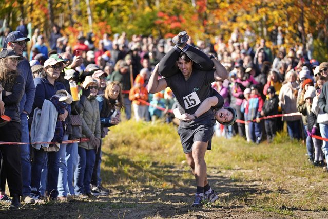 Nic Vinsonhaler carries Tara Rogowski while competing in the North American Wife Carrying Championship, Saturday, October 12, 2024, at Sunday River ski resort in Newry, Maine. (Photo by Robert F. Bukaty/AP Photo)