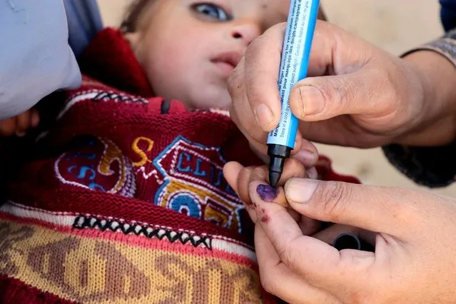 An Afghan health worker marks thumb of a child after administering polio vaccination, in the areas controlled by or under the influence of the Taliban, in Kandahar, Afghanistan, 26 January 2021. Vaccination campaign in Afghanistan resumed after seven months of break due to the Coronavirus pandemic. (Photo by Muhammad Sadiq/EPA/EFE)