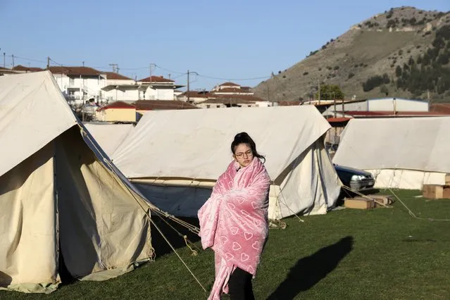 A girl standing outside a tent, uses a blanket to stay warm after an earthquake in Damasi village, central Greece, Thursday, March 4, 2021. Fearful of returning to their homes, thousands of people in central Greece spent the night outdoors after a powerful earthquake, felt across the region, damaged homes and public buildings. (Photo by Vaggelis Kousioras/AP Photo)
