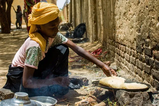 A girl prepares food outside at a camp for the internally displaced in al-Suwar, about 15 kilometres north of Wad Madani, on June 22, 2023. (Photo by AFP Photo/Stringer)
